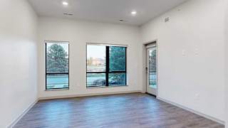 a spacious living room with a door and two large windows