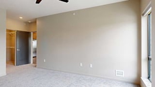A bedroom with floor-to-ceiling windows, a ceiling fan, and a walk-in closet.