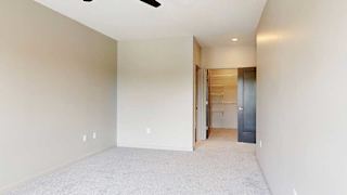 A bedroom with a ceiling fan, attached bathroom, and a walk-in closet.