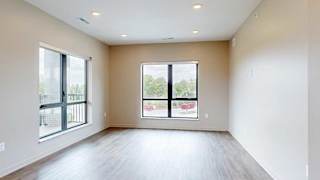 A living room with hardwood-style flooring and large floor-to-ceiling windows.