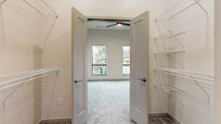 a walk-through closet with double doors opening into the bedroom