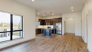 an open kitchen and living room with hardwood floors and a large window