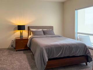 A bedroom with a large bed and a lamp on the side table.