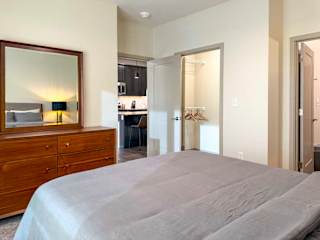 Bedroom with dresser and mirror, open closet, and view into kitchen.