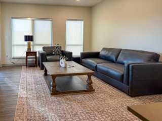 Living room with sofa, armchair, coffee table, and large windows.