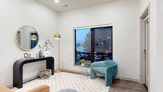 a studio apartment living area with a chair, small table, and wall-mounted artwork