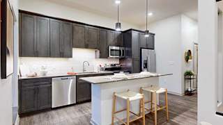 a kitchen with dark cabinets, tile backsplash, and stainless steel appliances