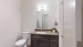 a bathroom with a quartz vanity sink and a mirror with overhead lighting