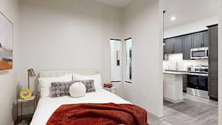 a bed with a red throw blanket and neutral-toned walls