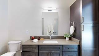 A bathroom with a quartz vanity, dark wooden cabinets, and a tall storage cabinet.