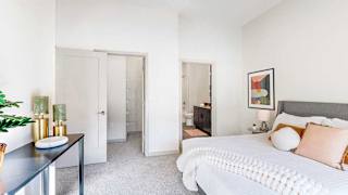 A bedroom with a bedding set, a walk-in closet, and an attached bathroom.