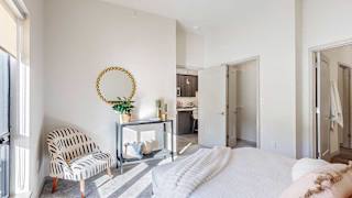 A furnished bedroom with modern furniture, a walk-in closet, and an attached bathroom.