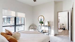 A furnished bedroom with a floor-to-ceiling window.