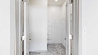 An L-shaped walk-in closet with several built-in shelves.