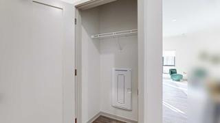 A hallway coat closet with a wire shelf.