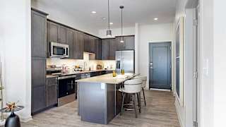 A kitchen with dark wooden cabinets, quartz countertops, an island, and stainless steel appliances.