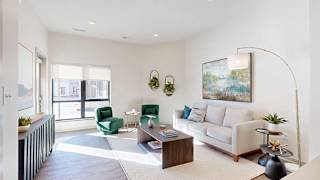 A living room with a white couch, two green arm chairs, and several modern furnishings.