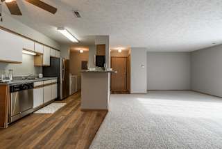 A kitchen with wooden floors that opens to living room