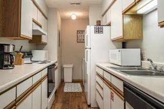 A kitchen with white appliances and white and oak cabinets.