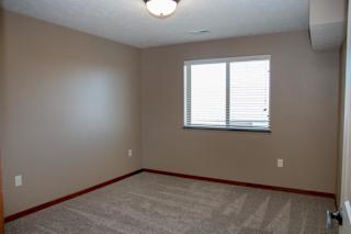 A room with a carpeted floor and a window with blinds.