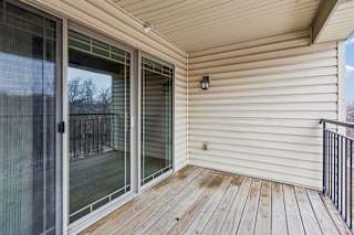 Covered apartment balcony featuring wood-plank flooring and railing.