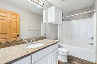 Apartment bathroom featuring white cabinetry, large mirror, and bathtub.