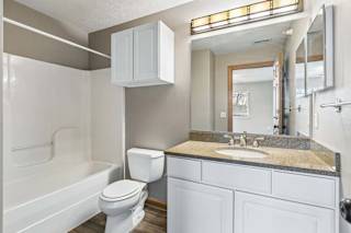 Bright bathroom with white vanity, granite counter, and tub.