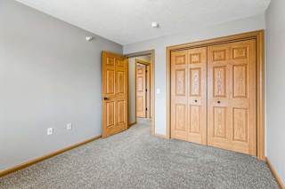 Unfurnished bedroom featuring neutral carpet and wood-trim closet doors.