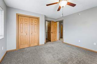 Carpeted bedroom with ceiling fan and double closet doors.