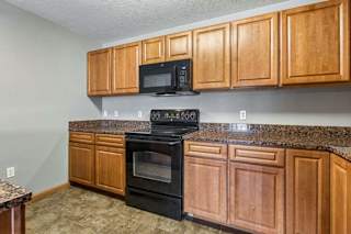 A kitchen with wooden cabinets and black appliances.