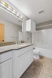 Bathroom with white vanity, granite countertop, and tub-shower.