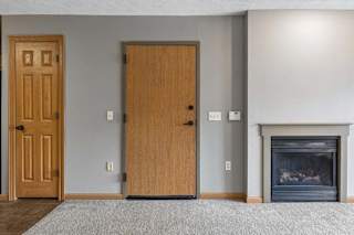 Living room view featuring entry door, fireplace, and neutral carpet.