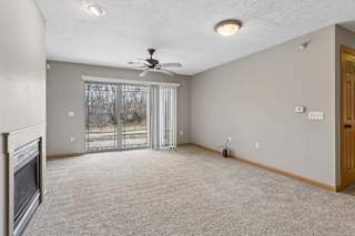 Spacious apartment living area featuring neutral carpet, fireplace, and patio access.