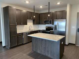 Large kitchen with dark brown cabinets, including island with room for seating