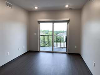 Wood floored living room with glass sliding door that opens onto balcony