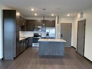 Large kitchen with dark brown cabinets, including island with room for seating