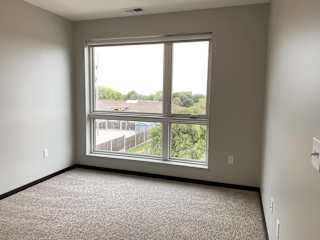 Carpeted bedroom with large floor to ceiling window looking out to north Lincoln