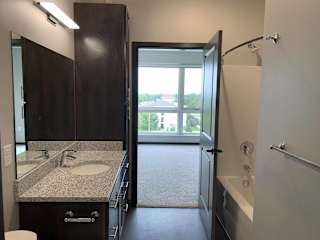 Bathroom with dark brown vanity and linen cabinet for storage and large mirror