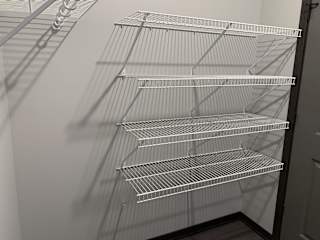 Walk in closet with one full wall of wire wracks for storage and hanging