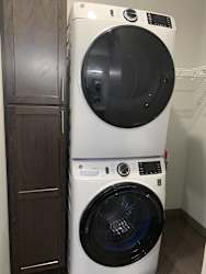 Stacked full size front load washer and dryer with linen storage in apartment in Lincoln