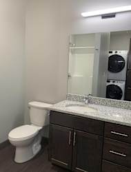 Bathroom with dark brown vanity with storage and large mirror at Haven at Uptown