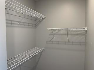 Large empty walk in closet with upper and lower wire racks for clothing storage