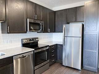 corner of kitchen with stainless steel appliances and warm brown cabinets for storage