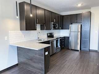 Open kitchen with mocha finish and stainless steel matching appliances in the nest floorplan at haven at uptown in lincoln nebraska