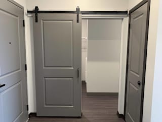 Hallway looking towards a barn door that encloses the walk in closet