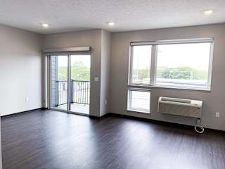 Living and sleeping area with bright windows and a sliding patio door