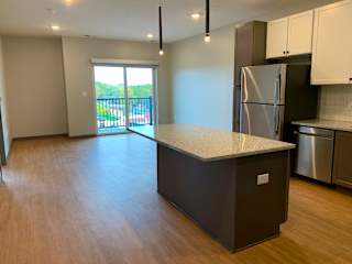 Open kitchen to dining room with large granite countertop island at Haven at Uptown in Lincoln, Nebraska