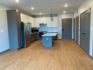 Open kitchen to dining room with large granite countertop island at Haven at Uptown in Lincoln, Nebraska