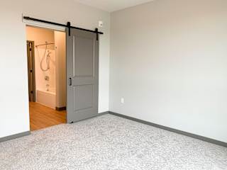 Sliding barn door leading to bathroom in master bedroom at Haven at Uptown in Lincoln, Nebraska