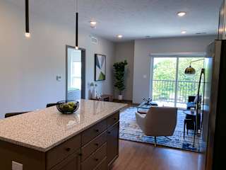 Large kitchen island and furnished living room looking out onto scenic view in Bliss floor plan at Haven at Uptown.
